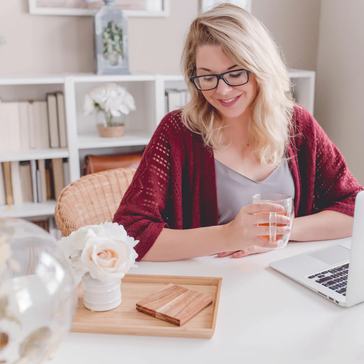 Smiling person with a mug working on a laptop at home
